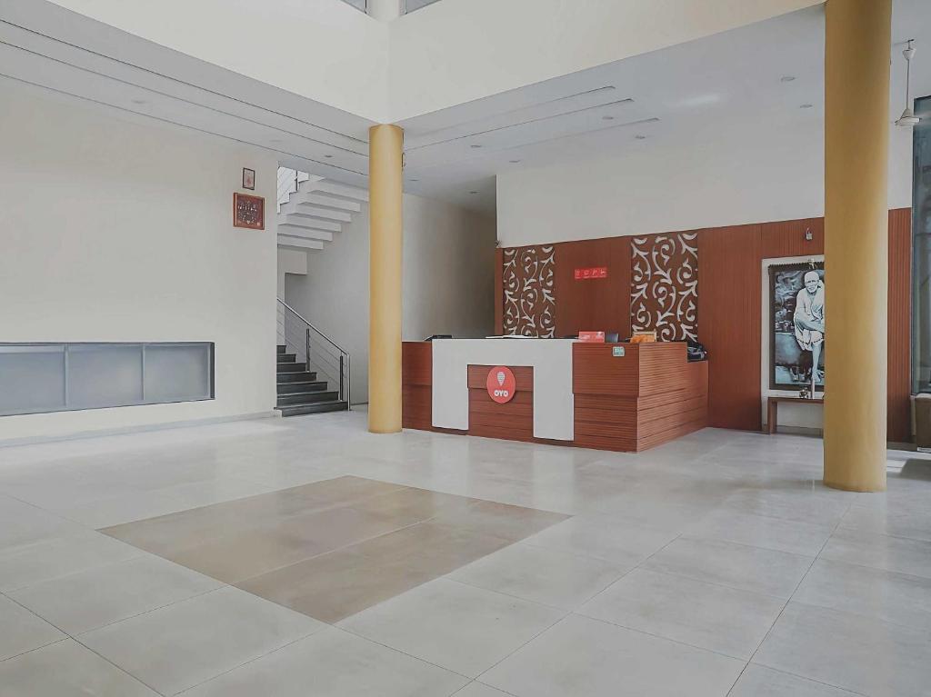シルディにあるCollection O 15845 Sanskruti Resortの柱のあるロビーとカウンターが備わる広い客室です。