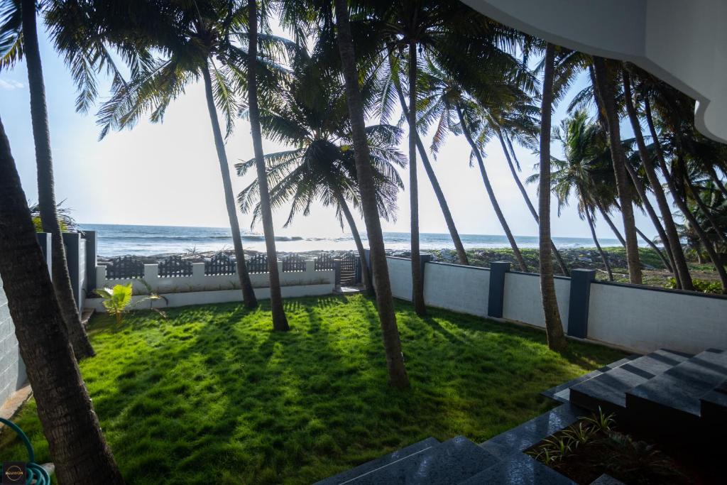 a view of the ocean from a balcony with palm trees at Reunion Ocean Manor - Beach House in Udupi