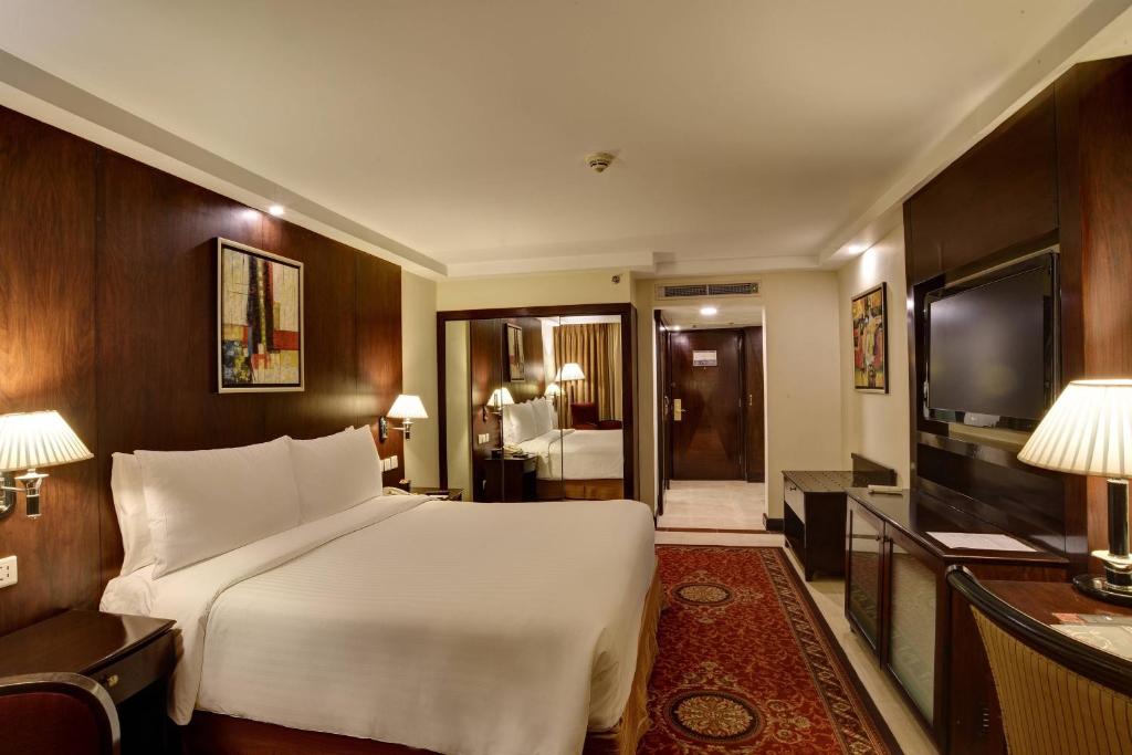 a bedroom with a large white bed and a television at Islamabad Marriott Hotel in Islamabad
