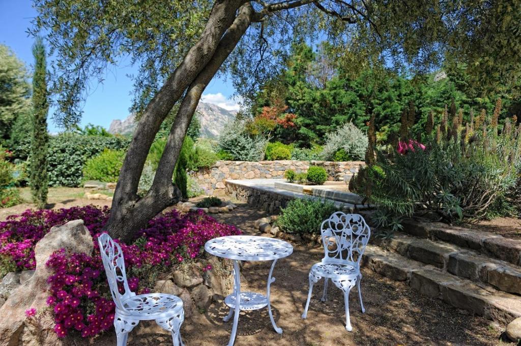 two chairs and a table in a garden with flowers at Chambre d'Hôtes Domaine Pero Longo in Sartène