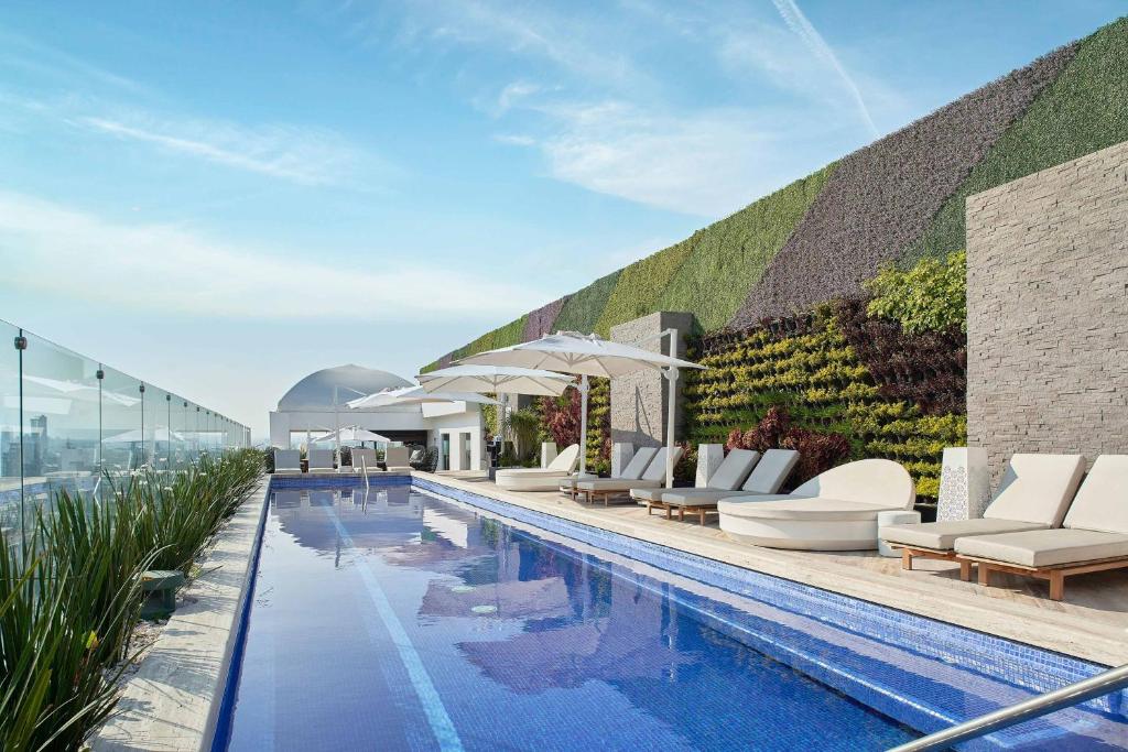 a pool with lounge chairs and umbrellas on a building at The Westin Monterrey Valle in Monterrey