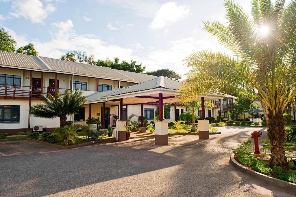 un bâtiment avec un palmier à côté d'une rue dans l'établissement Protea Hotel by Marriott Dar es Salaam Oyster Bay, à Dar es Salaam