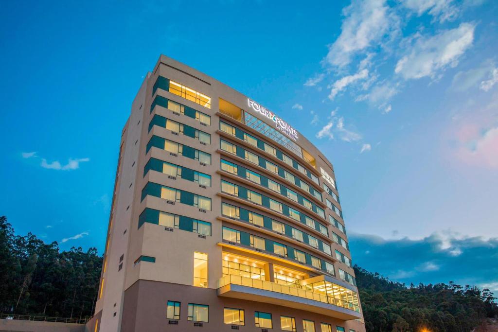 Four Points by Sheraton Cuenca في كوينكا: مبنى فندق طويل مع السماء في الخلفية