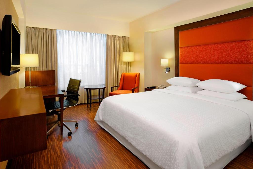 a hotel room with a large bed and a desk at Four Points by Sheraton Ahmedabad in Ahmedabad