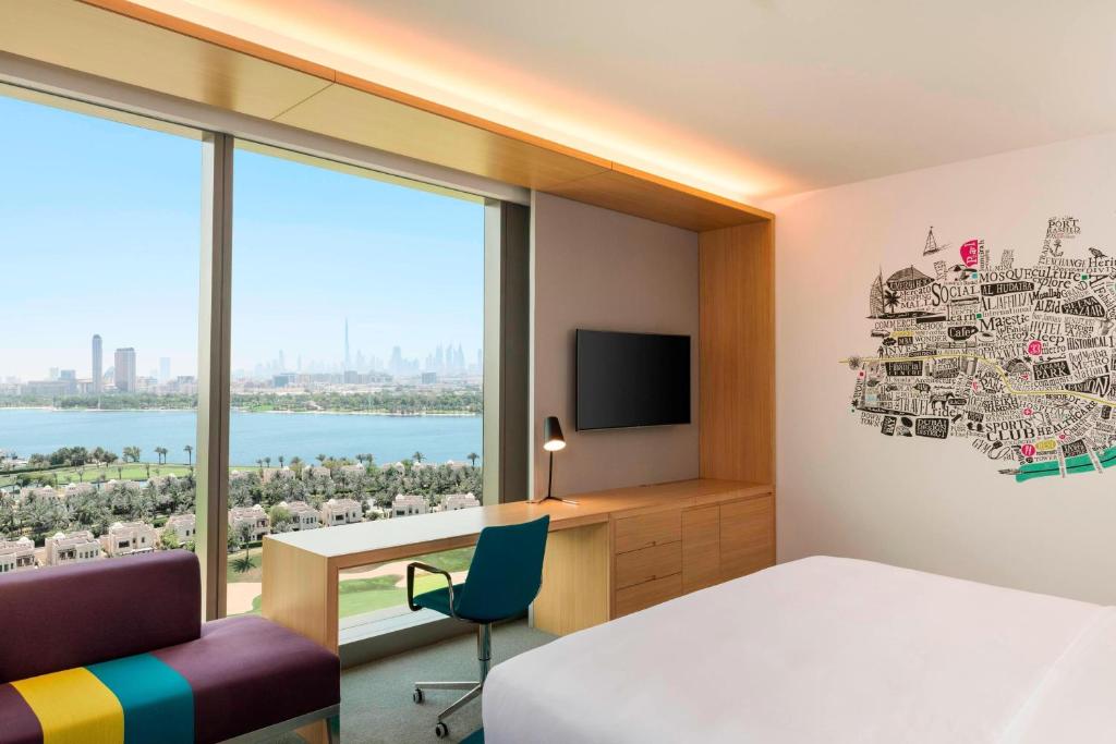 a bedroom with a bed and a desk and a tv at Aloft Dubai Creek in Dubai