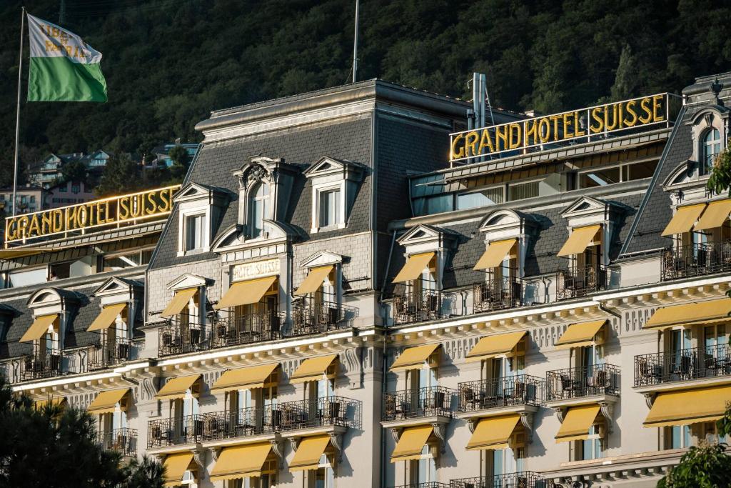 un grand bâtiment avec un drapeau en haut dans l'établissement Grand Hotel Suisse Majestic, Autograph Collection, à Montreux