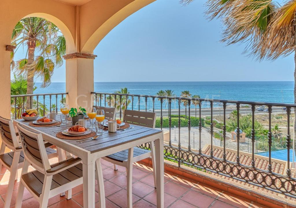 einen Tisch auf dem Balkon mit Blick auf den Strand in der Unterkunft Marina XI Lovely apartment inside Wyndham Resort in Mijas Costa