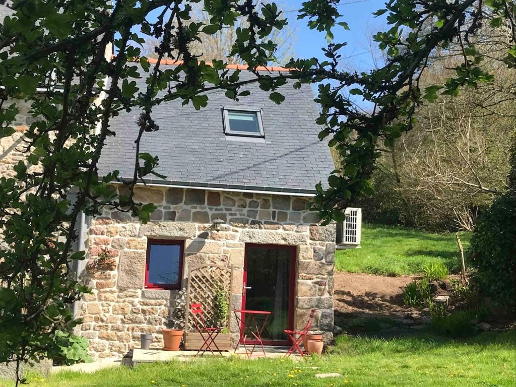 una pequeña casa de piedra con puerta roja en Gîte An Daou Tok, en Mellionnec
