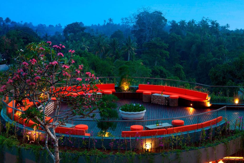 um pátio com sofás vermelhos, mesas e flores em Sthala, A Tribute Portfolio Hotel, Ubud Bali em Ubud