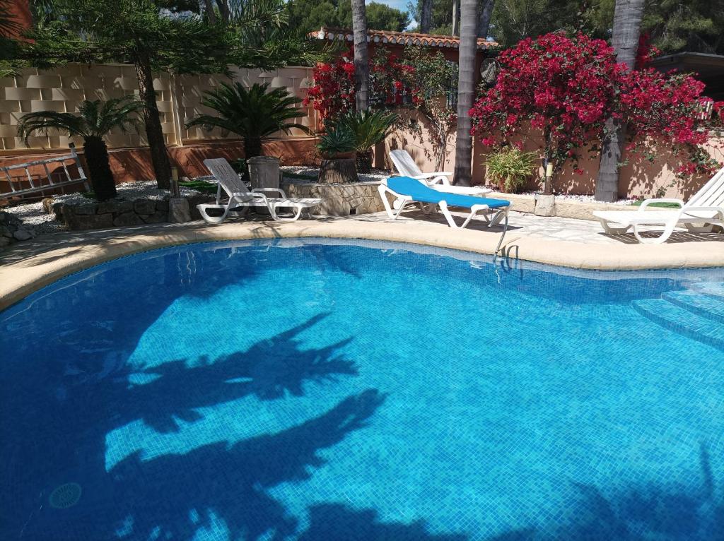 a large blue swimming pool with two lawn chairs at Vacaciones Denia 4 Rooms in Denia