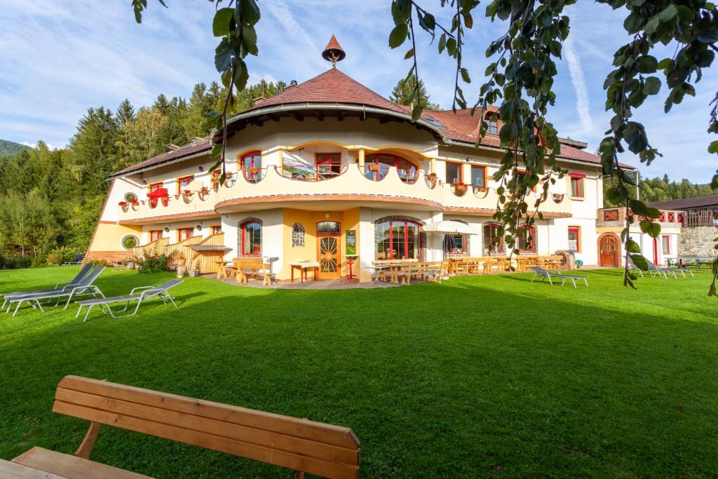 una grande casa con un cortile verde con una panchina di Biolandhaus Arche a Eberstein