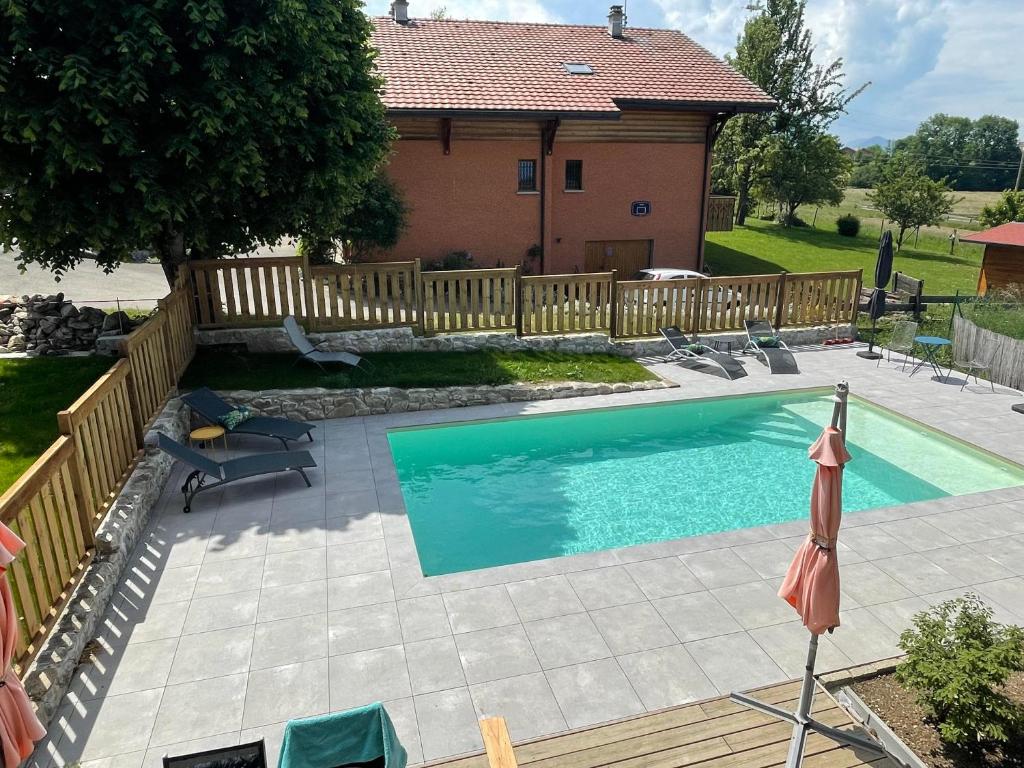 a swimming pool in front of a house with a fence at Maison d'hôtes des Bassins d'Oche in Saint-Paul-en-Chablais