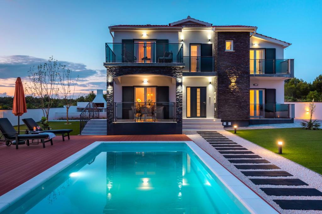 a villa with a swimming pool in front of a house at Villa Luna Luxury apartment in Skradin