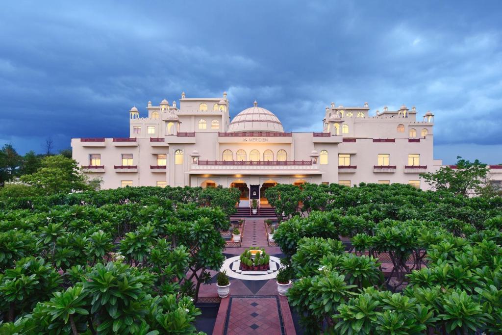 um grande edifício branco com árvores em frente em Le Meridien Jaipur Resort & Spa em Jaipur