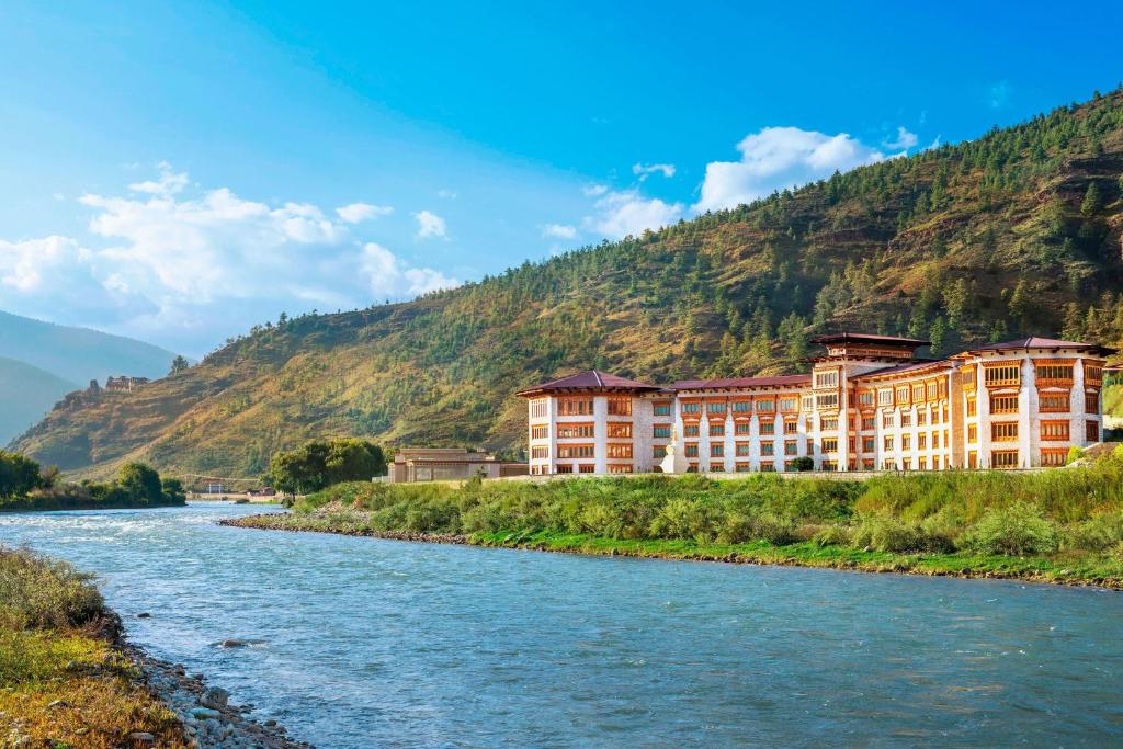 a building next to a river with a mountain at Le Meridien Paro Riverfront in Paro