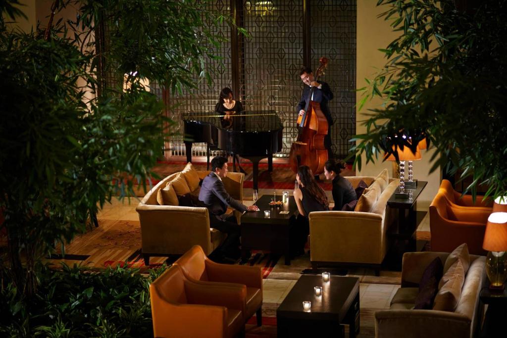 un grupo de personas sentadas en un vestíbulo con un piano en The Ritz-Carlton Beijing, Financial Street, en Beijing