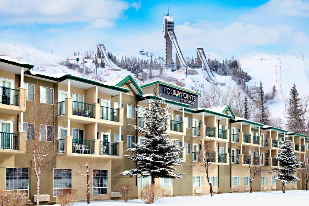 un hôtel dans la neige avec une remontée mécanique en arrière-plan dans l'établissement Four Points by Sheraton Hotel & Suites Calgary West, à Calgary