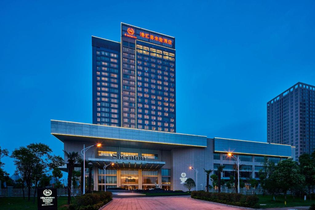 Un grand bâtiment avec des lumières allumées devant lui dans l'établissement Sheraton Chuzhou Hotel, à Chuzhou