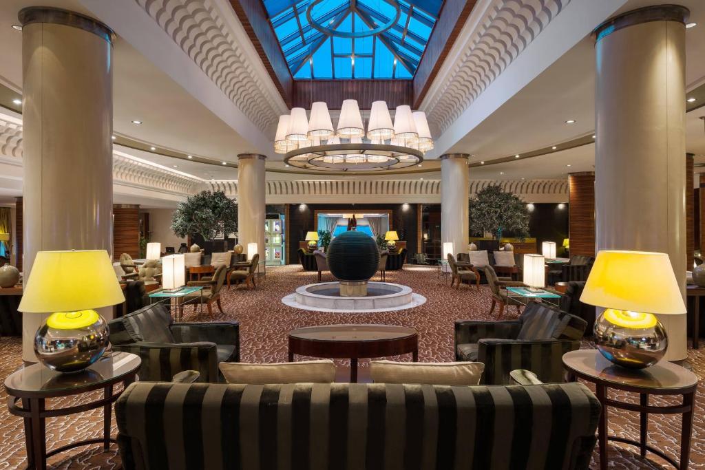 a hotel lobby with chairs and tables and a chandelier at Sheraton Dammam Hotel & Convention Centre in Dammam