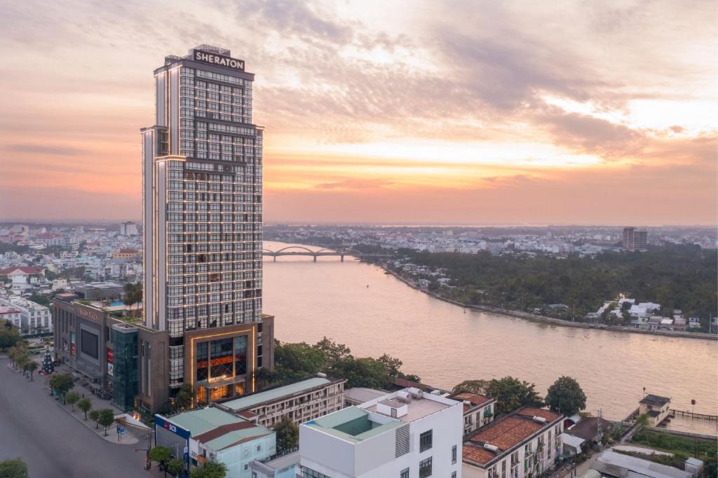 wysoki budynek obok rzeki z miastem w obiekcie Sheraton Can Tho w mieście Cần Thơ