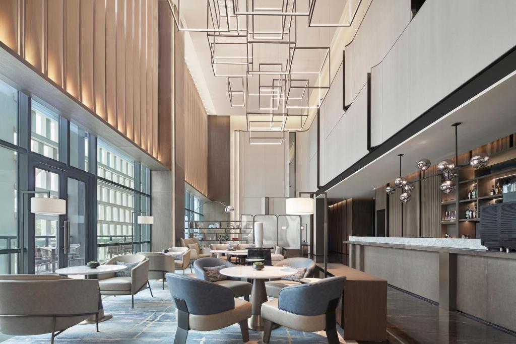 a lobby with tables and chairs and a bar at The Meixi Lake, Changsha Marriott Executive Apartments in Changsha