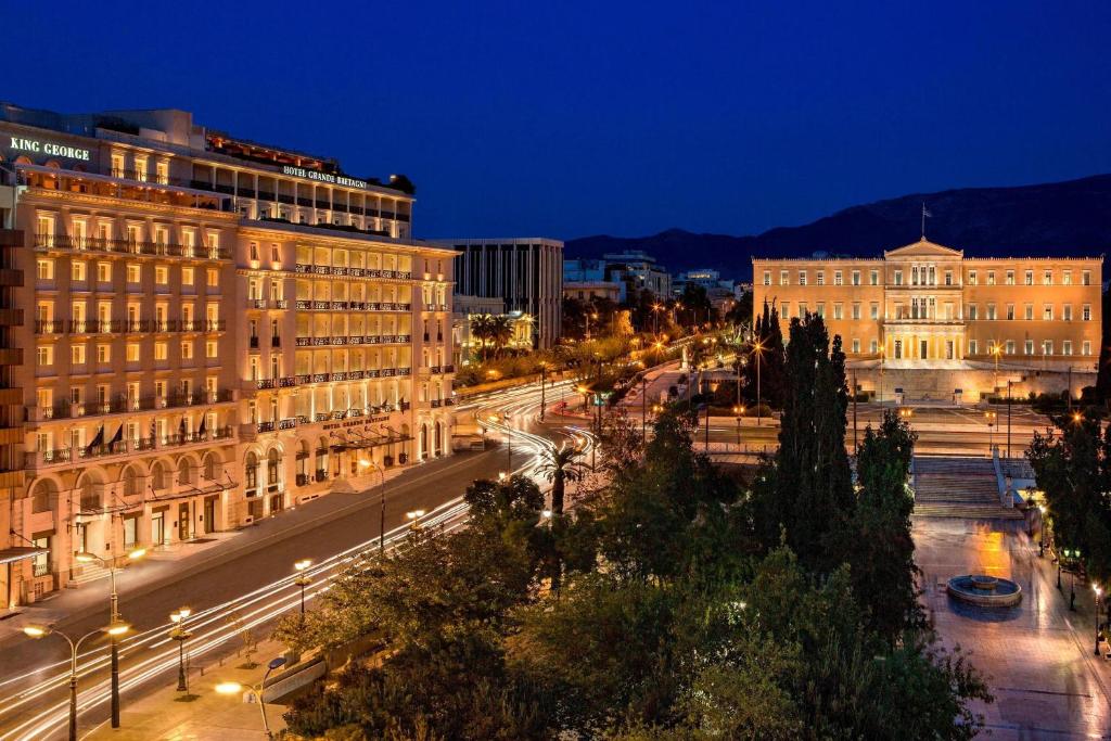 a city street with buildings and street lights at night at King George, a Luxury Collection Hotel, Athens in Athens