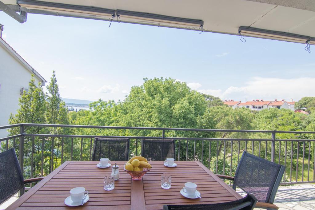 einen Holztisch mit einer Schale Obst auf dem Balkon in der Unterkunft Apartment Dina in Malinska