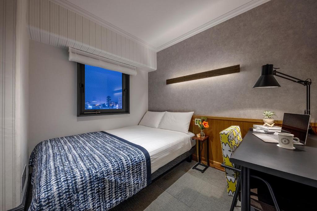 那覇市にあるエスティネートホテル那覇のベッドルーム1室(ベッド1台、デスク、窓付)