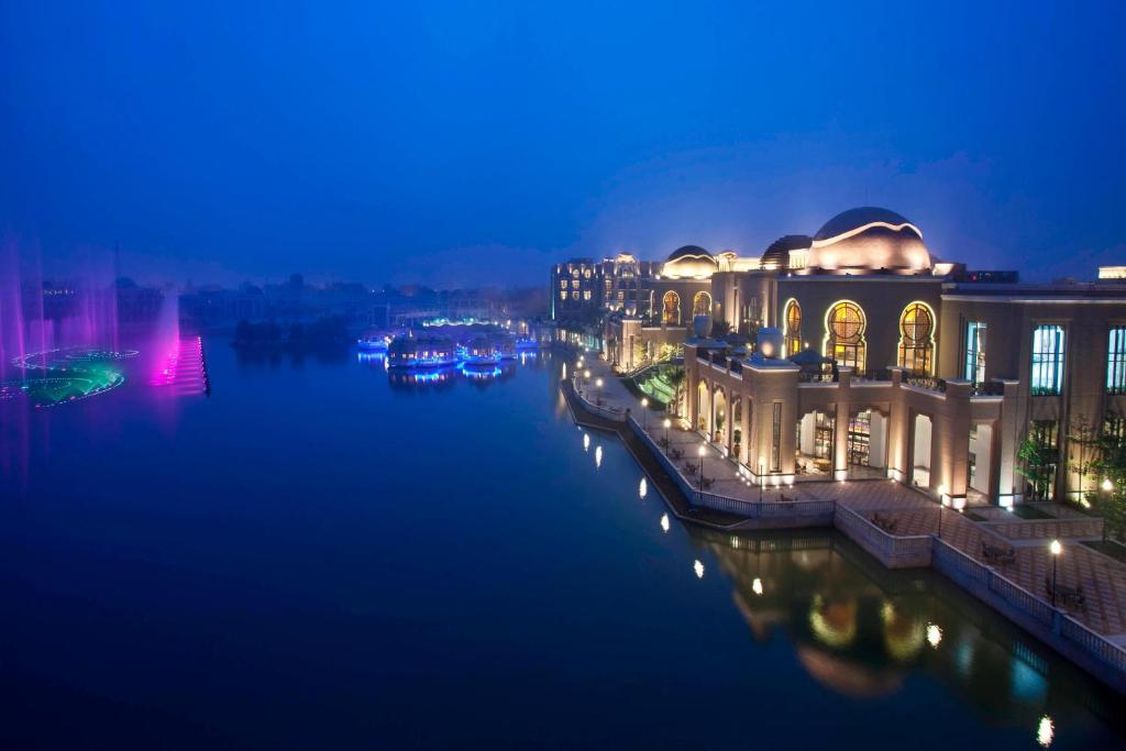 Sheraton Qingyuan Lion Lake Resort في تشينغيوان: مبنى بجانب نهر في الليل