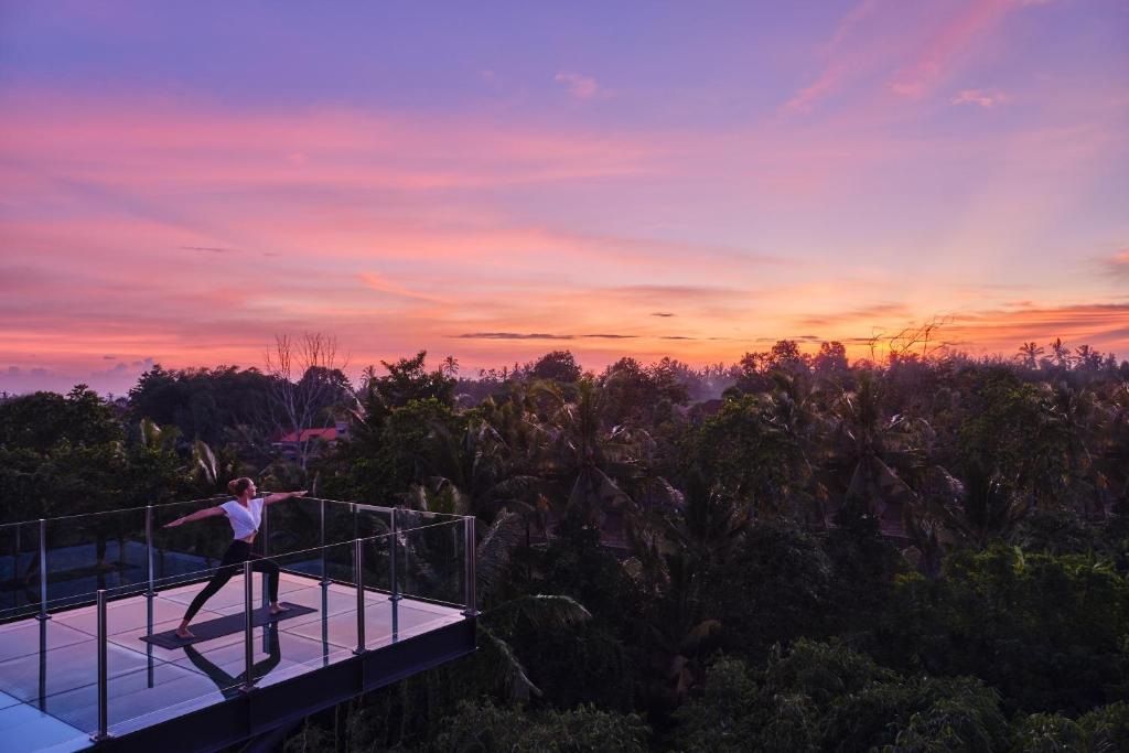 een persoon die op een uitkijkplatform staat bij zonsondergang bij Element Bali Ubud in Ubud