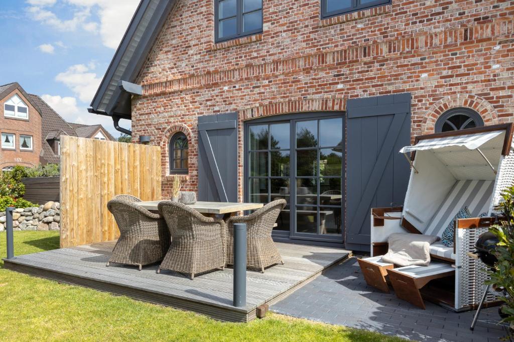 eine Terrasse mit Korbstühlen und einem Tisch im Hof in der Unterkunft Ferienhaus Finoah - Leben, Luxus, Leichtigkeit hinter der Duene in Westerland Sylt in Westerland