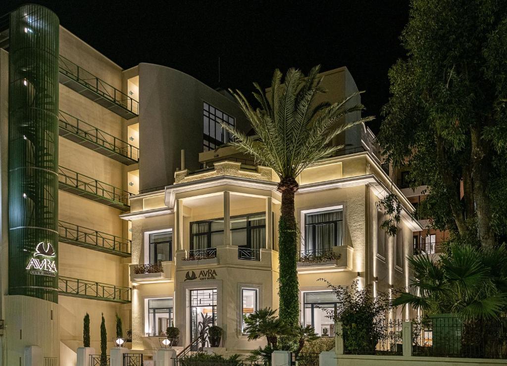 a building with a palm tree in front of it at Avra City Boutique Hotel in Chania