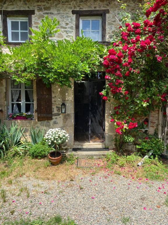 une maison avec des fleurs roses et une porte noire dans l'établissement Red Gate Cottage, à Saulgond