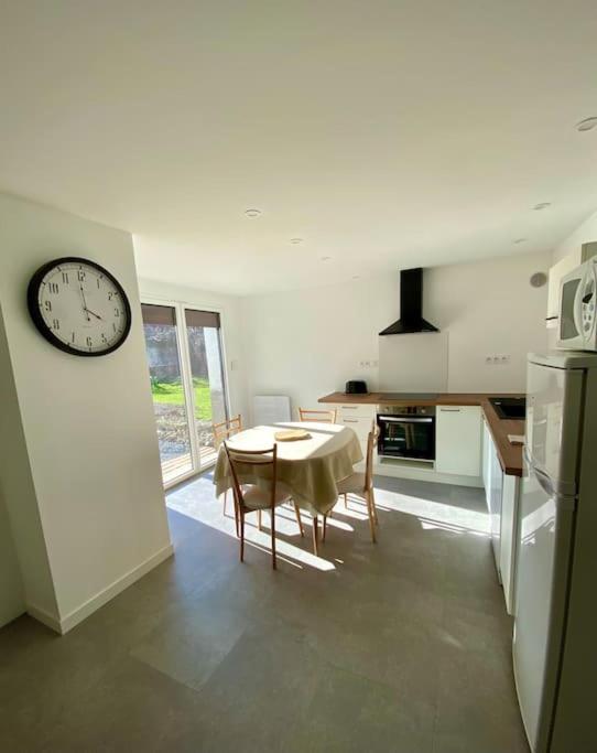 a kitchen with a table and a clock on the wall at REZ DE JARDIN AU COEUR DES PYRENEES in Agos-Vidalos