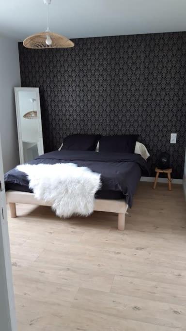 a bedroom with a bed with a black and white blanket at REZ DE JARDIN AU COEUR DES PYRENEES in Agos-Vidalos