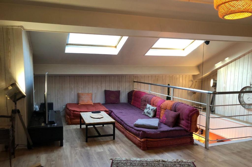 a living room with a purple couch and a skylight at Pour la période des Jeux Olympiques 2024 seulement Duplex de 4 chambres à 100 mètres de Paris for Olympics 2024 only 4 bedroom duplex 100 meters from Paris in Montrouge