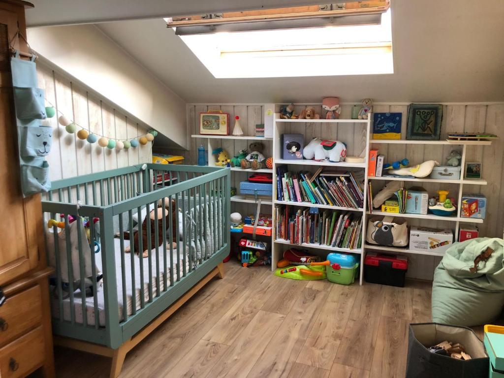 a nursery with a crib and book shelves at Pour la période des Jeux Olympiques 2024 seulement Duplex de 4 chambres à 100 mètres de Paris for Olympics 2024 only 4 bedroom duplex 100 meters from Paris in Montrouge