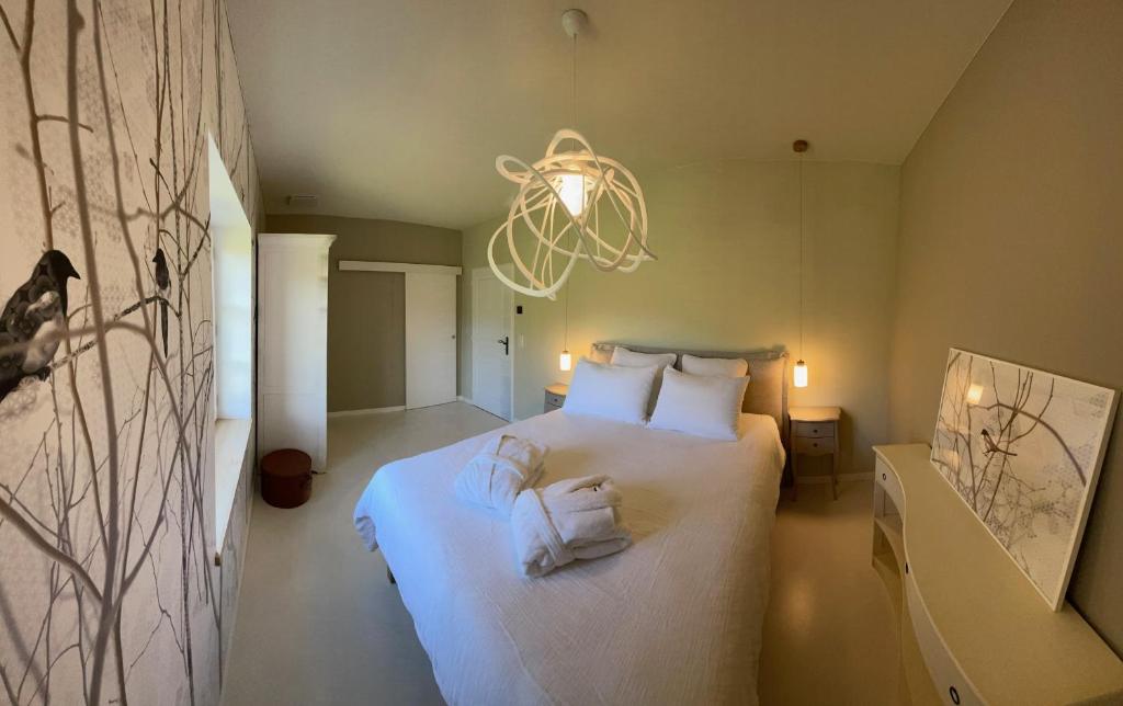 a bedroom with a bed with white sheets and a chandelier at Le Clos Des Buis Gîte de Charme Cocoonoïte in Cazals