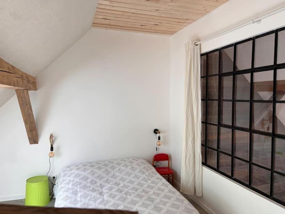 a bedroom with a bed and a large window at Le grenier a foin in Breitenbach-Haut-Rhin