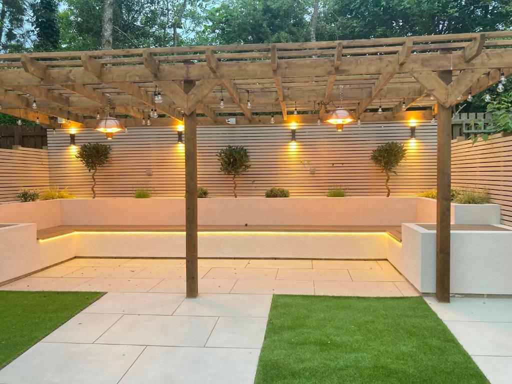 a patio with a pergola with lights and grass at Greensfield Close 