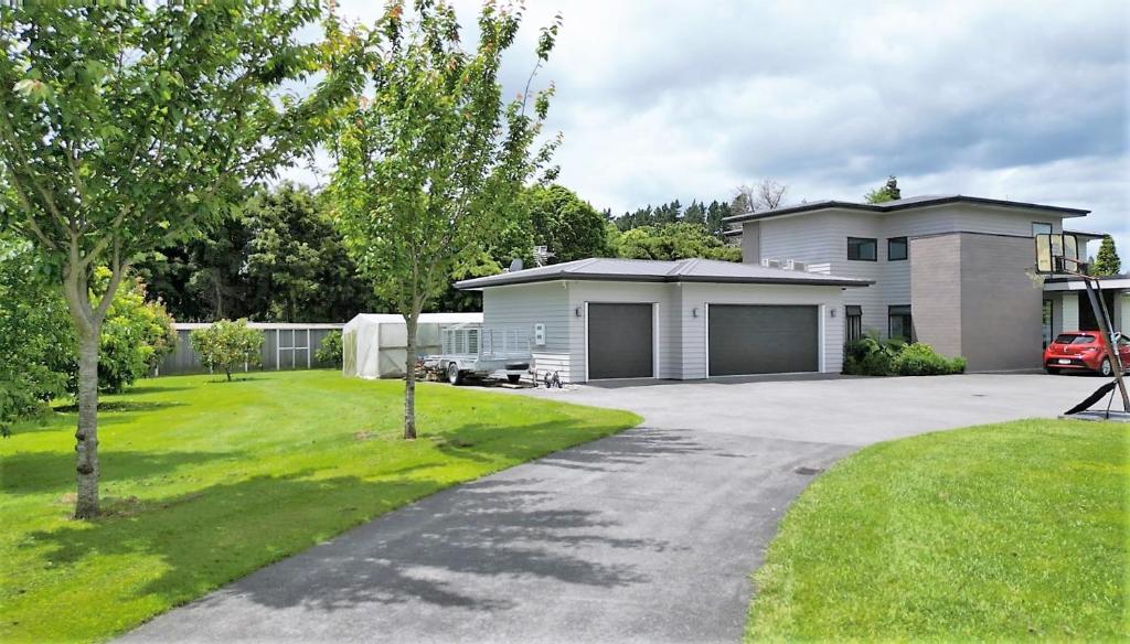 a house with a car parked in front of a driveway at Tamahere Lifestyle in Tamahere