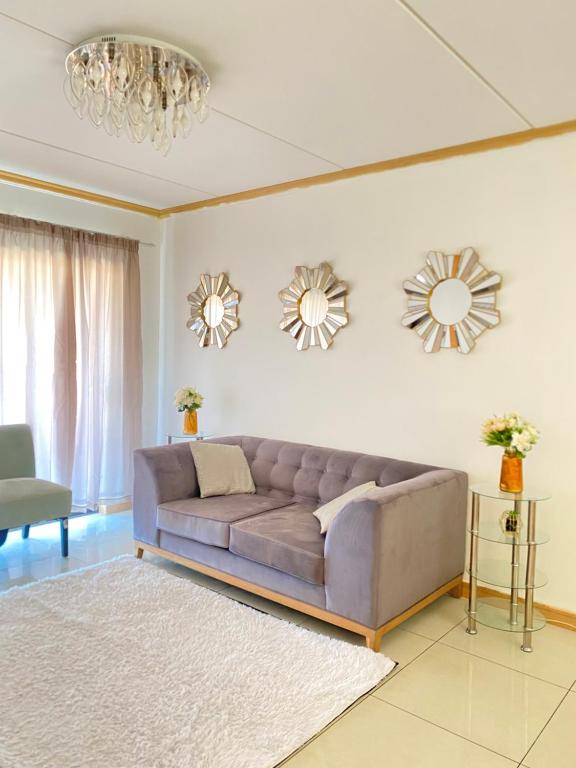 sala de estar con sofá y 2 espejos en Siena Sun Apartment 6 with water reserve, en Midrand