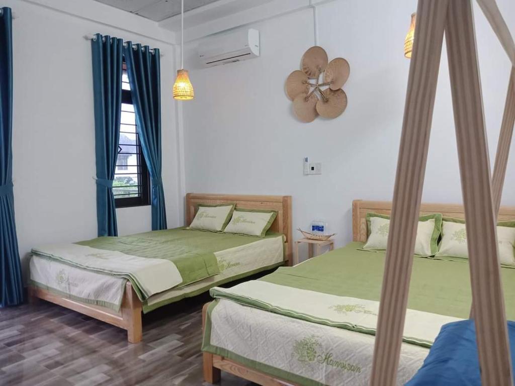 a bedroom with two beds and a fan on the wall at Xuka Homestay in Hue