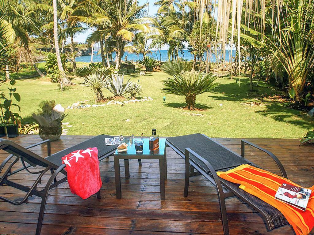a table and chairs on a deck with a view of the ocean at Villa Ibiscus in Las Galeras