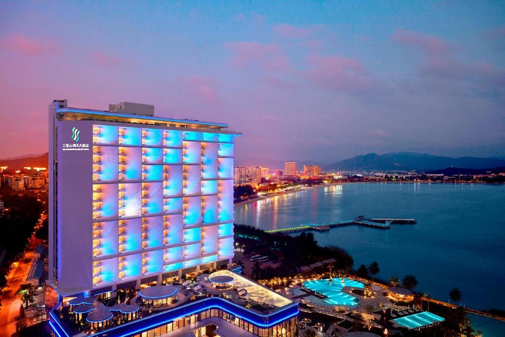 een verlicht gebouw naast een waterlichaam bij The Shanhaitian Resort Sanya, Autograph Collection in Sanya