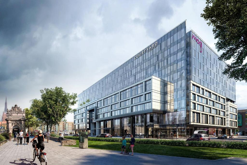 a man riding a bike in front of a building at Moxy Szczecin City in Szczecin