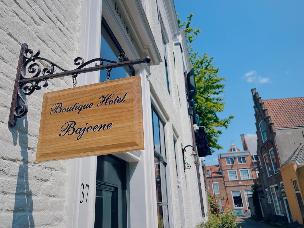 ein Holzschild, das an der Seite eines Gebäudes hängt in der Unterkunft Boutique Hotel Bajoene in Middelburg