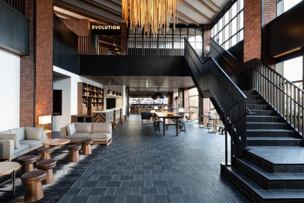 a lobby with a staircase and tables and chairs at Four Points by Sheraton Nagoya, Chubu International Airport in Tokoname