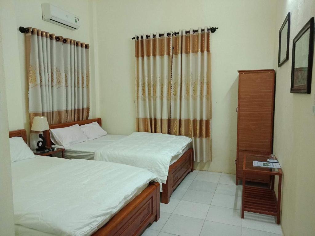 1 dormitorio con 2 camas, vestidor y cortinas en Quy Phuong - Homestay, en Tân Hiệp