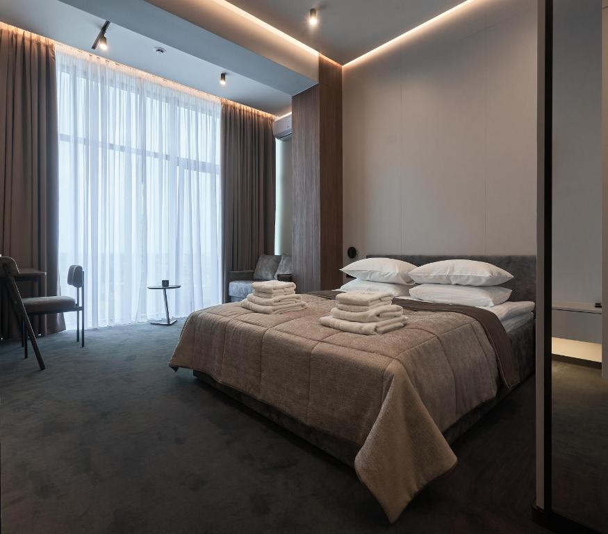 a bedroom with a large bed with towels on it at WHITE HILLS HOTEL spa&sport in Uzhhorod